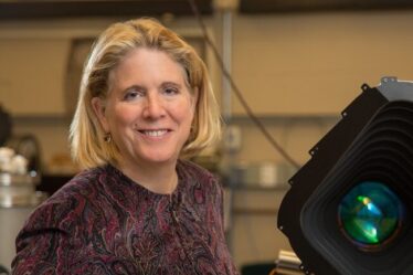 Jacqueline Hewitt stands with a prototype of one of the four cameras aboard the Transiting Exoplanet Satellite Survey (TESS) instrument.