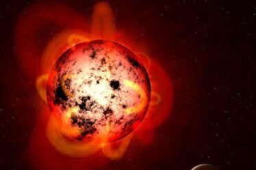 An illustration of a red dwarf star orbited by an exoplanet.