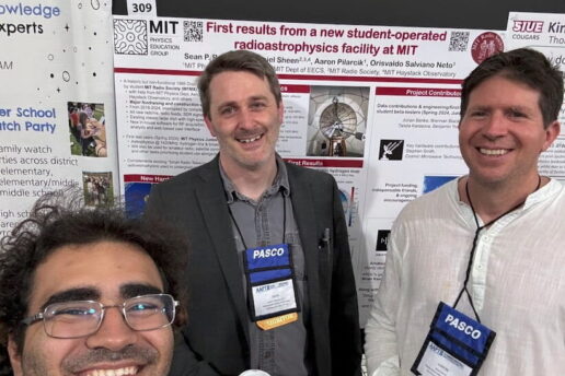 three people pose in front of physics posters